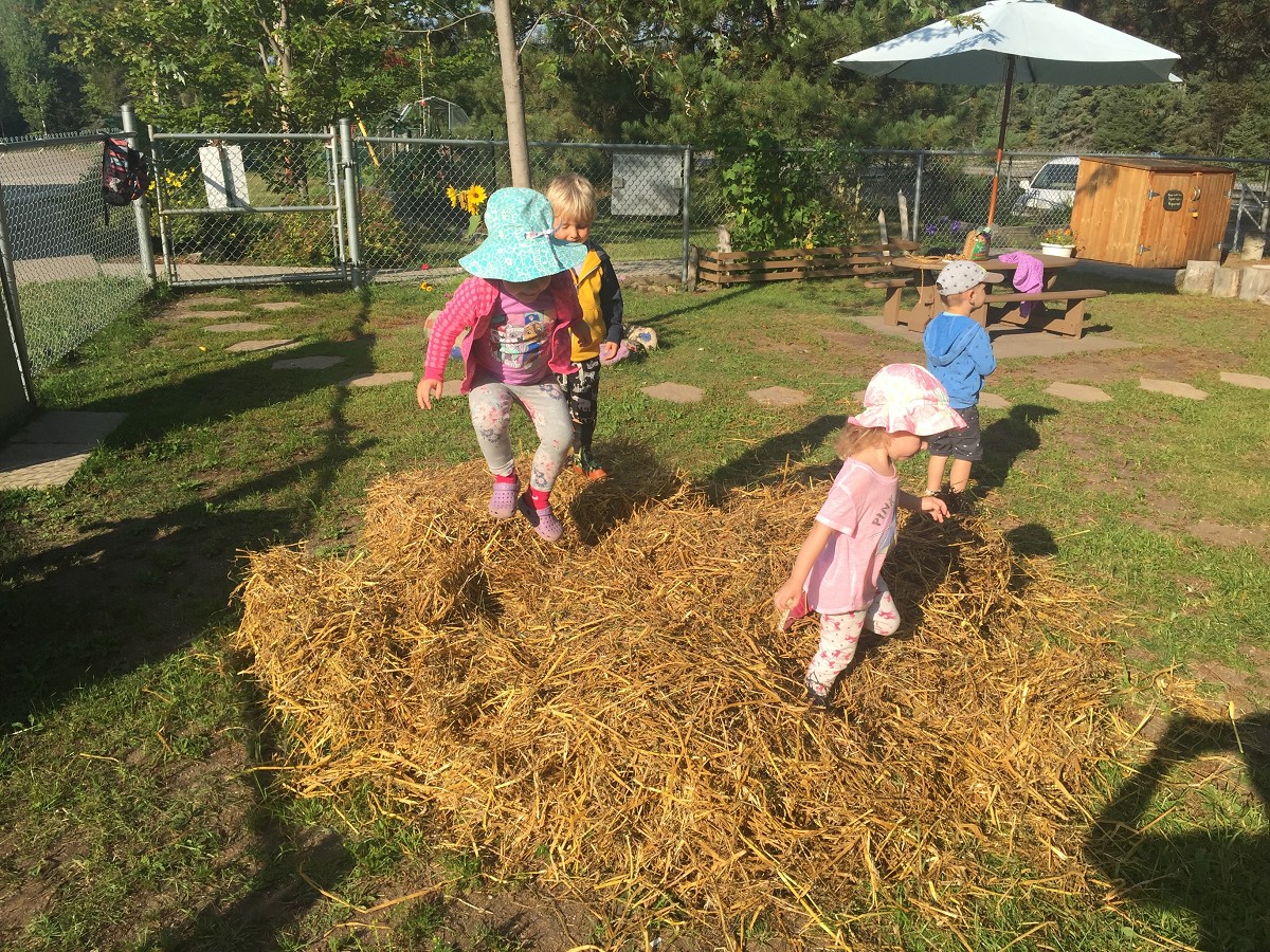 kids playing in a hay pile